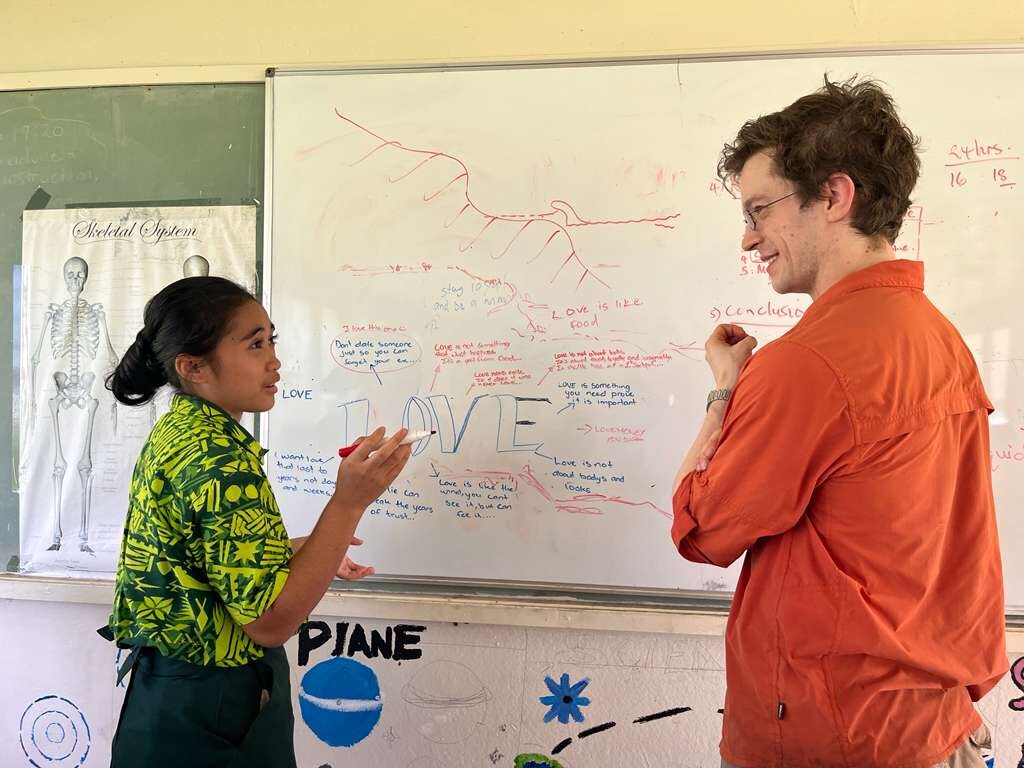 Cook Islands student and HISEAS field team member discussing a board drawing during a school visit.