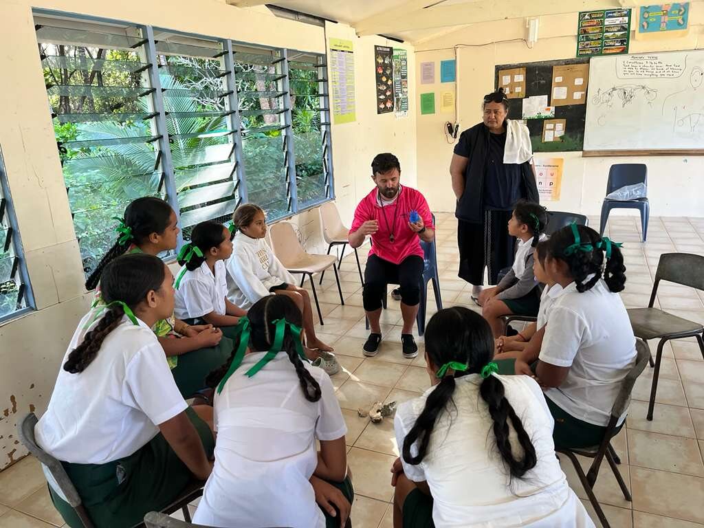 HISEAS field team member speaking with Cook Islands students seated in a classroom circle.